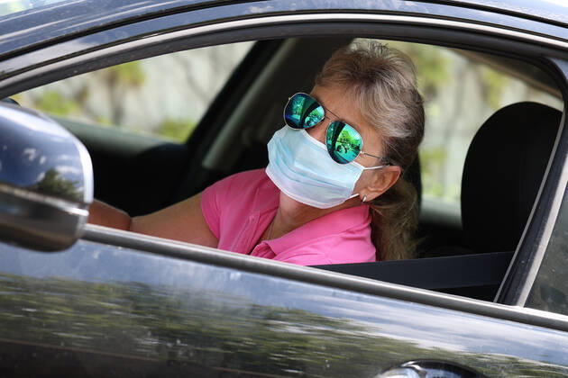 Symbolfoto, Corona-Krise, Bußgeld, Frau am Lenkrad eines PKW mit Maske, Mundschutz,