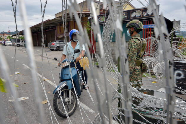 (200426) -- KUALA LUMPUR, April 26, 2020 (Xinhua) -- A soldier stands guard next to a community under the enhanced movement control order in Selayang Baru, Selangor, Malaysia, on April 26, 2020. The number of new COVID-19 cases in Malaysia was kept at a double-digit for a 10th day in a row on Sunday after 38 new cases were reported, bringing the total cases to 5,780, the Health Ministry said. (Photo by Chong Voon Chung Xinhua) MALAYSIA-SELANGOR-COVID-19 