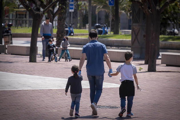 April 26, 2020, Barcelona, Spain: Parents walk with their children on the street during the first day of allowing kids to move out for one hour with an adult..First day on the street, after 42 days of confinement, for children under 14 accompanied by an adult. The rides are limited to one hour and a maximum distance of one kilometre due to the contagion of the Covid 19. Barcelona Spain - ZUMAs197 20200426_zaa_s197_039 Copyright: xPacoxFreirex
