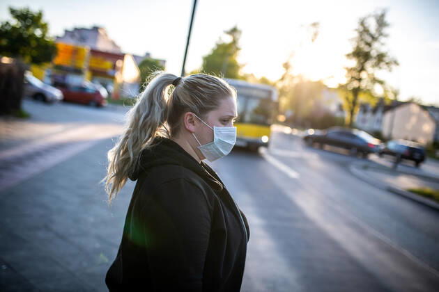 Ein Frau mit einer Mund-Nasen-Maske an einer Bushaltestelle der BVG in Berlin während ein Bus einfährt. Ab Montag, den 27. April 2020 gilt eine Maskenpflicht im ÖPNV. Maskenpflicht im ÖPNV