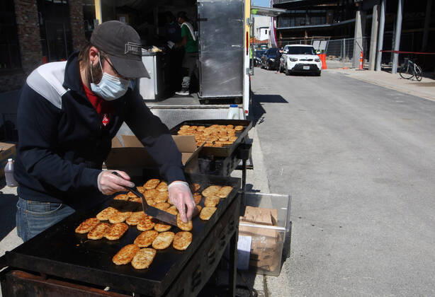 A volunteer cooks hash brown as cars wait for prepared sandwiches, in St. Louis on Sunday, April 26, 2020. Hundreds of cars lined the streets for an opportunity to receive food from several restaurants, while the group took donations for theThe Gateway Resilience Fund, an organization that assists fellow restaurant workers that are out of work because of the coronavirus.  SLP2020042607 BILLxGREENBLATT