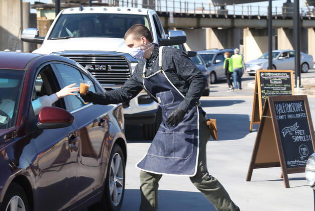 A volunteer hands off a coffee to one of many that have waited in their cars for free food, in St. Louis on Sunday, April 26, 2020. Hundreds of cars lined the streets for an opportunity to receive food from several restaurants, while the group took donations for theThe Gateway Resilience Fund, an organization that assists fellow restaurant workers that are out of work because of the coronavirus.  SLP2020042612 BILLxGREENBLATT