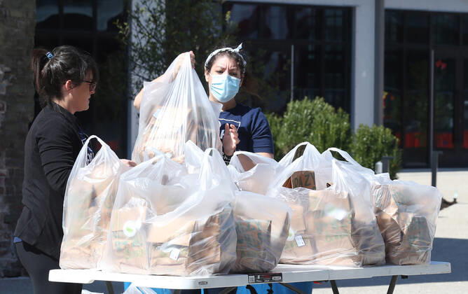 Volunteers stack food for the many that have waited in their cars for free food, in St. Louis on Sunday, April 26, 2020. Hundreds of cars lined the streets for an opportunity to receive food from several restaurants, while the group took donations for theThe Gateway Resilience Fund, an organization that assists fellow restaurant workers that are out of work because of the coronavirus.  SLP2020042615 BILLxGREENBLATT
