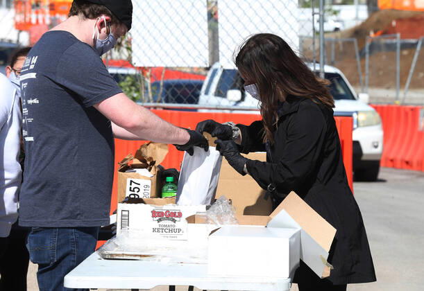 Volunteers prepare a bag of sandwiches, that will be given to one of many that have waited in their cars for free food, in St. Louis on Sunday, April 26, 2020. Hundreds of cars lined the streets for an opportunity to receive food from several restaurants, while the group took donations for theThe Gateway Resilience Fund, an organization that assists fellow restaurant workers that are out of work because of the coronavirus.  SLP2020042616 BILLxGREENBLATT