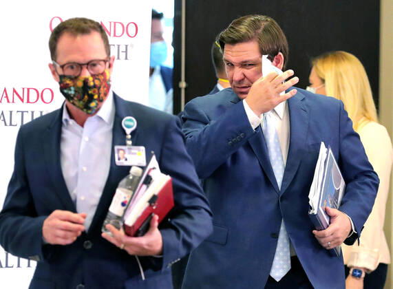 April 26, 2020, Orlando, FL, USA: Florida Gov. Ron DeSantis removes his face mask as he arrives for a press briefing on the state s status in the coronavirus crisis, at Orlando Health s Orlando Regional Medical Center, Sunday, April 26, 2020. All the speakers participating in the briefing removed their masks to deliver remarks and answer questions. DeSantis arrives with Orlando Health President & CEO David Strong, left. Orlando USA - ZUMAm67_ 20200426_zaf_m67_008 Copyright: xJoexBurbankx
