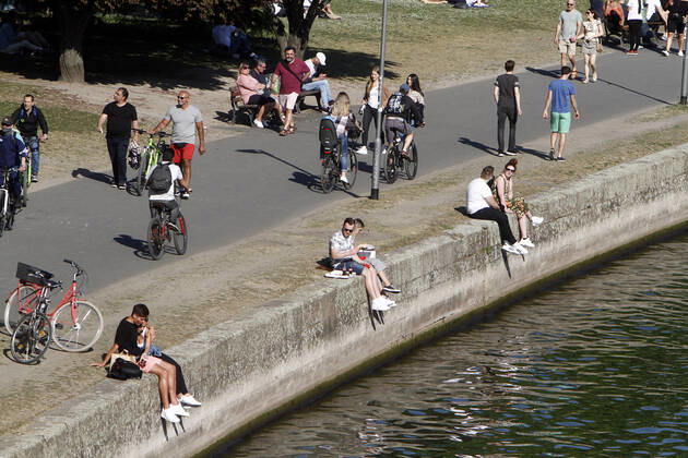 Passanten genießen den warmen Frühlingstag und den Sonnenschein bei einem Spaziergang auf der Uferpromenade am Main in Frankfurt, Hessen, Deutschland