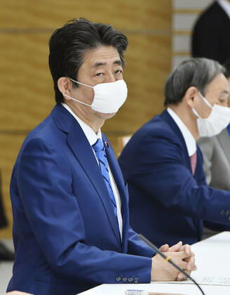 New coronavirus Japanese Prime Minister Shinzo Abe (L) attends a meeting of the government task force on combatting the new coronavirus pandemic in Tokyo on April 27, 2020. 