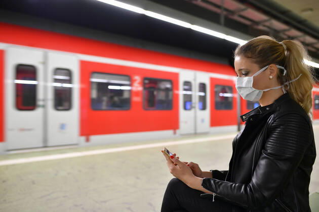 Frau mit Mundschutzmaske, am Handy, wartet auf Zug, S-Bahn, Station Stadtmitte, Corona-Krise, Stuttgart, Baden-Württemberg, Deutschland Coronavirus