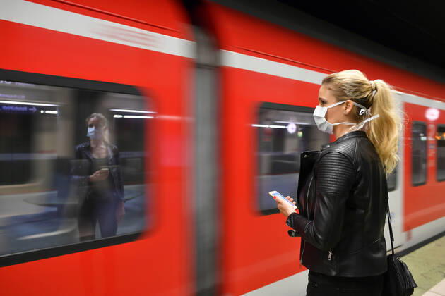 Frau mit Mundschutzmaske, am Handy, wartet auf Zug, S-Bahn, Spiegelung im Fenster, Corona-Krise, Stuttgart, Baden-Württemberg, Deutschland Coronavirus