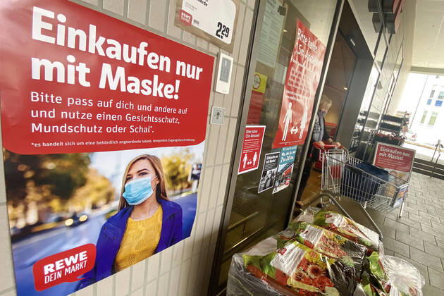Lockerungen und Maskenpflicht in der Coronavirus Pandemie: Geschaefte in Bayern oeffnen am 27.April wieder. Ein Schild weist auf das Tragen von Mund Nasenschutz hin.Maskenpflicht. REWE Supermarkt Ladengeschaeft ,Filiale,Eingang,