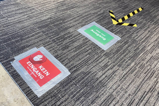 Lockerungen und Maskenpflicht in der Coronavirus Pandemie: Geschaefte in Bayern oeffnen am 27.April wieder. Markierung am Fussboden weissen auf Ausgang in einer Hugendubel Buchhandlung hin. Einbahnstrasse,Einbahnregel. Ladengeschaeft ,Filiale,Eingang,