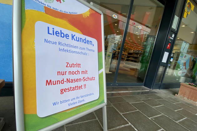 Lockerungen und Maskenpflicht in der Coronavirus Pandemie: Geschaefte in Bayern oeffnen am 27.April wieder. Hinweis,Aufsteller vor einer Sani Plus Apotheke: Zutritt nur noch mit Mund-Nasen-Schutz gestattet. Ladengeschaeft ,Filiale,Eingang,