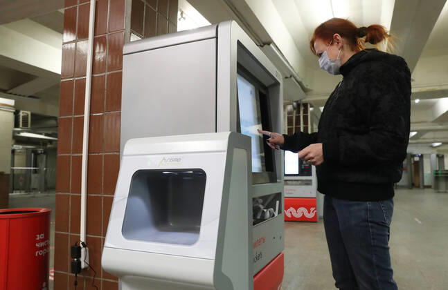 MOSCOW, RUSSIA - APRIL 27, 2020: A commuter in a face mask at a touch screen ticket machine at the entrance to a deserted Komsomolskaya Station of the Moscow Underground (metro), during the pandemic of the novel coronavirus disease (COVID-19). Seen in the foreground is a contactless hand sanitiser machine. Since 30 March, Moscow has been on lockdown. On 13 April 2020, the Moscow government introduced a digital permit system aimed at further restricting movement. Under the scheme, which became mandatory on 15 April, people need to apply for permits to travel on a vehicle or public transport around the city. As of 27 April 2020, Russia has reported more than 87,300 confirmed cases of the novel coronavirus infection, with more than 45,300 confirmed cases in Moscow. Vladimir Gerdo TASS  TS0D7349