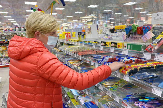 Lockerungen und Maskenpflicht in der Coronavirus Pandemie: Geschaefte in Bayern oeffnen am 27.April wieder. Eine Frau mit Mund-Nasen-Schutz in der Schreibwarenabteilung in einem Drogeriemarkt . Ladengeschaeft ,Filiale,Eingang,