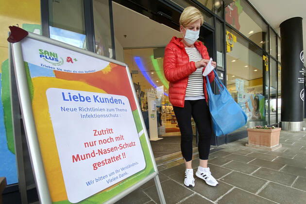 Lockerungen und Maskenpflicht in der Coronavirus Pandemie: Geschaefte in Bayern oeffnen am 27.April wieder. Eine Frau mit Mund-Nasen-Schutz kommt aus einer SaniPlus Apotheke neben einem Hinweis,Aufsteller -Zutritt nur noch mit Mund-Nasen-Schutz gestattet. Ladengeschaeft ,Filiale,Eingang,