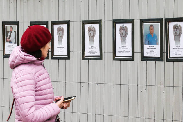 ST PETERSBURG, RUSSIA - APRIL 28, 2020: A woman by portraits of medical workers who died after contracting the novel coronavirus by the offices of St Petersburg s Healthcare Committee in Malaya Sadovaya Street. The wall of memory was created by St Petersburg resident Irina Maslova. Peter Kovalev TASS  TS0D7527