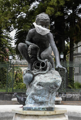 A protective mask is placed on a statue of a child fisherman, in street riviera, in Naples city. Government Decree declaring all of Italy a protected area to combat Covid-19 - Coronavirus infection. Copyright: xSalvatorexLaportax xIPAx xKontrolabx