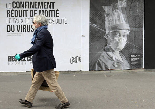 A passer-by wears a mask as he walks past a Covid-19 poster in the streets of Paris, France, Tuesday April 28, 2020. The French premier announced today that protective masks, which have been in severe shortage since the outbreak of the pandemic, will be available for everyone starting May 11th.  PAR20200428101 ECOxCLEMENT