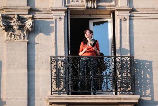 A resident bangs a cooking pan with a wooden spoon from her balcony to make noise for health workers in Paris, France, Tuesday April 28, 2020 as country enters its 6th week of confinement. The French premier announced today that protective masks, which have been in severe shortage since the outbreak of the pandemic, will be available for everyone starting May 11th.  PAR20200428109 ECOxCLEMENT