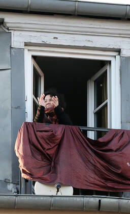 A resident applauds health workers from her balcony in Paris, France, Tuesday April 28, 2020 as country enters its 6th week of confinement. The French premier announced today that protective masks, which have been in severe shortage since the outbreak of the pandemic, will be available for everyone starting May 11th.  PAR20200428110 ECOxCLEMENT