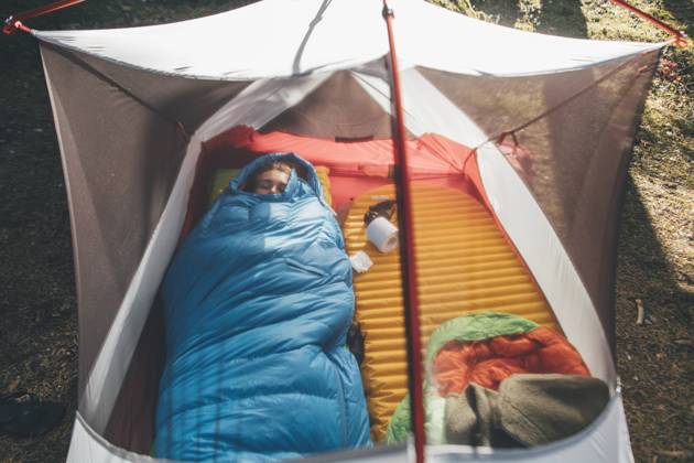 Young woman sleeping in sleeping bag in a tent model released Symbolfoto GUSF03701
