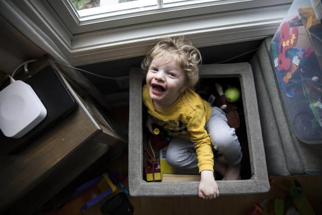 IMAGO Creative: Jahreszeit Winter, Fantasievoll drinnen spielen Laughing Boy Sits in Toy Box Next to Storage Bins Looks Up at Camera Easton, MD, United States CR_EMJA200506A-357579-01,model released, Symbolfoto