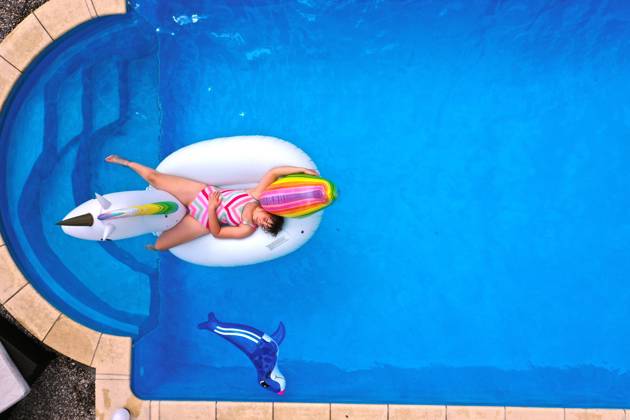26.06.2020, Trend in der Corona-Pandemie: Der eigene Swimmingpool im Garten sorgt im Sommer für Erfrischung wenn die Freibäder geschlossen haben. Luftaufnahme eines Gartenpools im Unterallgäu. Teenager schwimmt im Wasser auf einem Gummi-Einhorn. (Modelreleased) 26.06.2020, Swimmingpool im eigenen Garten 26.06.2020, Swimmingpool im eigenen Garten