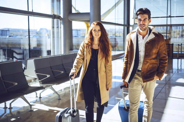 Confident business couple standing with luggage at airport departure area model released Symbolfoto EHF00444