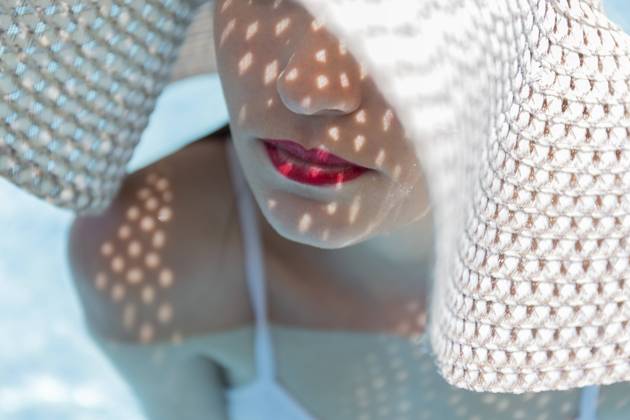 Close-up of young woman with red lipstick on lips wearing hat in swimming pool model released Symbolfoto JPTF00554