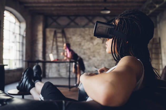 Young woman relaxing in armchair in loft office wearing Vr goggles model released Symbolfoto property released MEUF00740