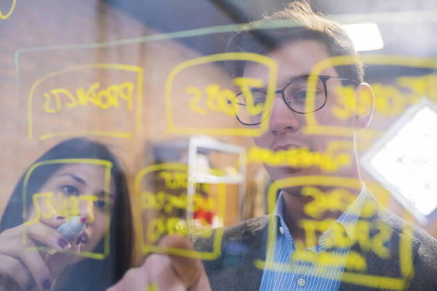 Businessman and woman brainstorming taking notes on glass pane in office model released Symbolfoto property released MEUF00850