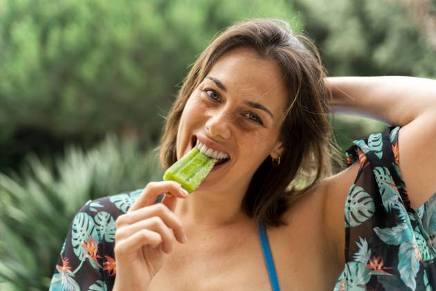 Happy young woman eating popsicle at yard model released Symbolfoto AFVF06813