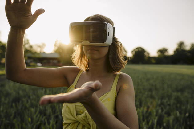 Young woman wearing VR goggles in a grain field in the countryside model released Symbolfoto property released GUSF04281