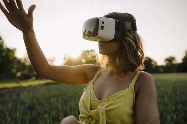 Young woman wearing VR goggles in a grain field in the countryside model released Symbolfoto property released GUSF04282