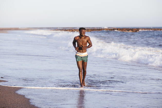 Shirtless African young man running at shore against clear sky model released Symbolfoto property released LJF01707