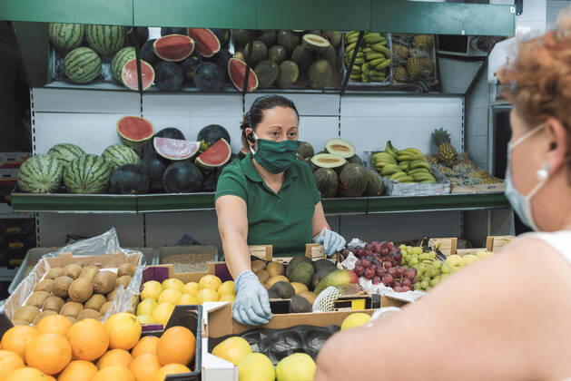 a shopkeeper with a mask attends to a customer in the greengrocer s. Torredelcampo, AL, Spain CR_NNSU200920A-508742-01 ,model released, Symbolfoto ,property released
