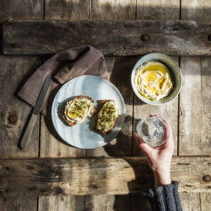 IMAGO Creative, Food, Hummus Hand of woman holding glass of water and plate with bread slices with hummus and sprouts model released Symbolfoto EVGF03726