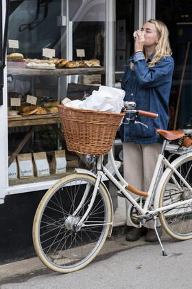 Young blond woman standing next to bicycle outside waste free wholefood store. United Kingdom,Young blond woman standing next to bicycle outside waste free wholefood store. Young blond woman standing next to bicycle outside waste free wholefood store.