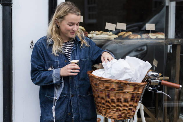 Young blond woman standing next to bicycle outside waste free wholefood store. United Kingdom,Young blond woman standing next to bicycle outside waste free wholefood store. Young blond woman standing next to bicycle outside waste free wholefood store.