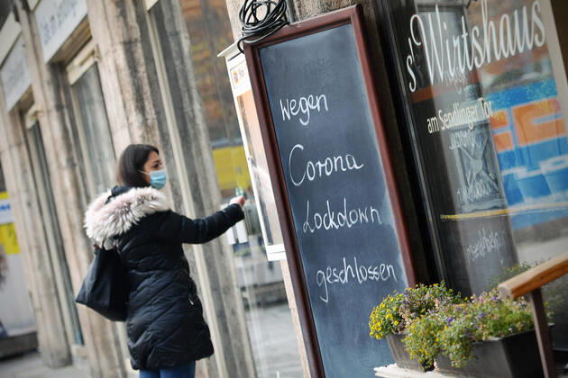 Themenbild: Coronavirus Pandemie Folgen fuer die Gastronomie. Eine Junge Frau steht mit Mundschutz,Maske vor einer verschlossenen Tuere eines Wirtshauses neben einem Schild: WEGEN CORONA LOCKDOWN GESCHLOSSEN, Geschlossenes bayerisches Restaurant am Sendlinger Tor in Muenchen. Seit dem 2.November muss wegen dem Lockdown light die Gastronomie geschlossen bleiben, Schliessung-Folge der Corona Pandemie,Lockdown,Shutdown,Inzidenzwert. MODEL RELEASED!