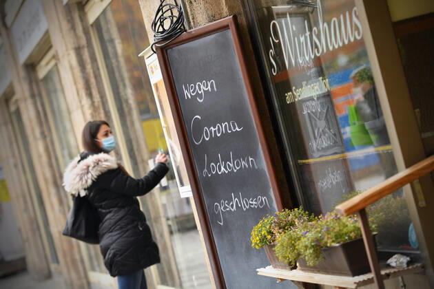 Themenbild: Coronavirus Pandemie Folgen fuer die Gastronomie. Eine Junge Frau steht mit Mundschutz,Maske vor einer verschlossenen Tuere eines Wirtshauses neben einem Schild: WEGEN CORONA LOCKDOWN GESCHLOSSEN, Geschlossenes bayerisches Restaurant am Sendlinger Tor in Muenchen. Seit dem 2.November muss wegen dem Lockdown light die Gastronomie geschlossen bleiben, Schliessung-Folge der Corona Pandemie,Lockdown,Shutdown,Inzidenzwert. MODEL RELEASED!