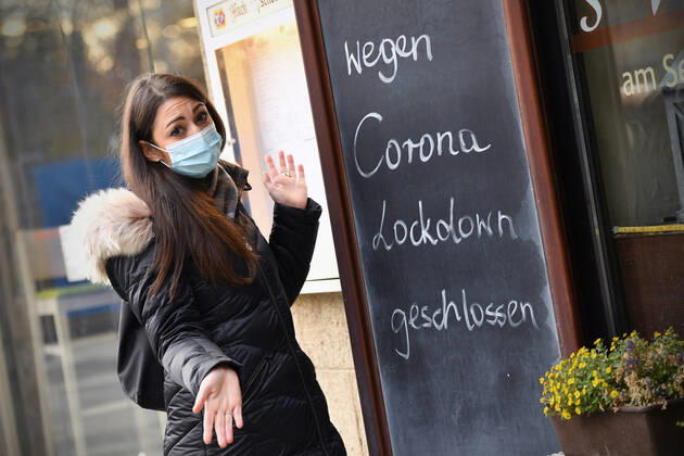 Themenbild: Coronavirus Pandemie Folgen fuer die Gastronomie. Eine Junge Frau steht mit Mundschutz,Maske ratlos vor einem Schild: WEGEN CORONA LOCKDOWN GESCHLOSSEN, Geschlossenes bayerisches Restaurant am Sendlinger Tor in Muenchen. Seit dem 2.November muss wegen dem Lockdown light die Gastronomie geschlossen bleiben, Schliessung-Folge der Corona Pandemie,Lockdown,Shutdown,Inzidenzwert. MODEL RELEASED!