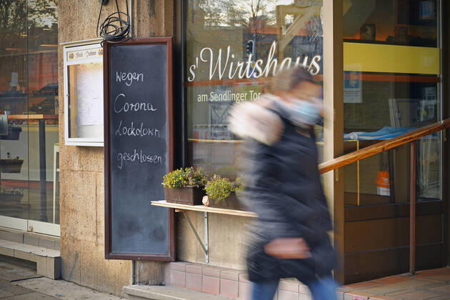 Themenbild: Coronavirus Pandemie Folgen fuer die Gastronomie. Schild am Wirtshaus am Sendlinger Tor; WEGEN CORONA LOCKDOWN GESCHLOSSEN, eine junge Frau,Passantin geht vorbei. Geschlossenes bayerisches Restaurant am Sendlinger Tor in Muenchen. Seit dem 2.November muss wegen dem Lockdown light die Gastronomie geschlossen bleiben, Schliessung-Folge der Corona Pandemie,Lockdown,Shutdown,Inzidenzwert. MODEL RELEASED!