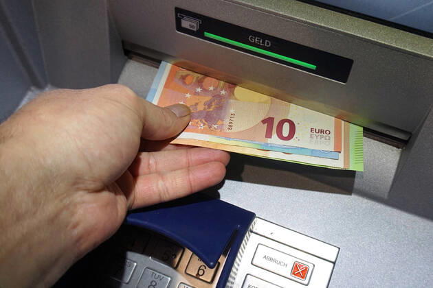 Bargeldversorgung aus einem Automat Eine Person holt an einem Geldautomaten Bargeld ab