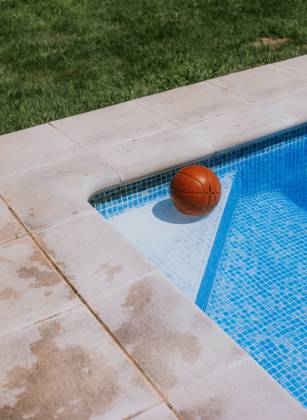 From above of basketball ball in corner on swimming pool in terrace of house with green grass Copyright: xEkaitzxGeriquex Model Released