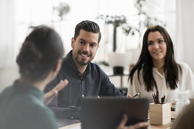 Smiling colleagues looking at businesswoman showing laptop during meeting , model released, property released Copyright: xMaskotx , MA53107