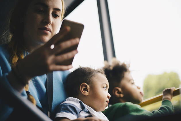 Mother using mobile phone while sitting with son in bus , model released Copyright: xMaskotx , MA57524
