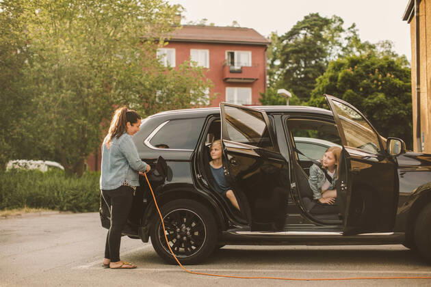IMAGO Creative: Klimawandel - Zukunft und Innovation Girls looking at smiling mother charging electric car at station , model released Copyright: xMaskotx , MA68576