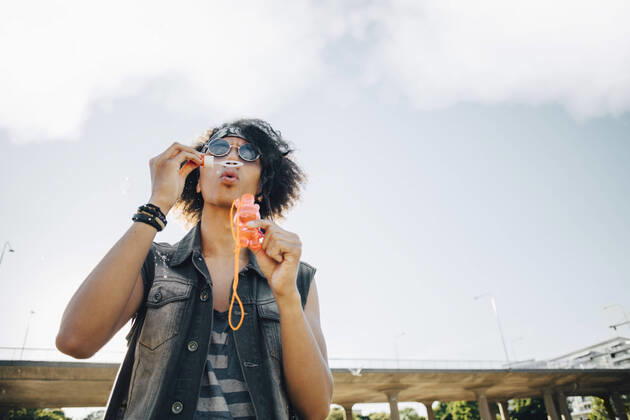 Low angle view of young man blowing soap bubbles against sky , model released Copyright: xMaskotx , MA69884