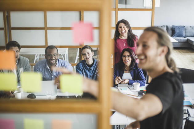Smiling colleagues looking at businessman explaining strategy in meeting seen through glass wall , model released, property released Copyright: xMaskotx , MA72721